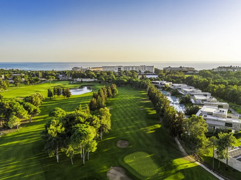 Kaya Palazzo Golf Club from the air in late light, running down towards the sea