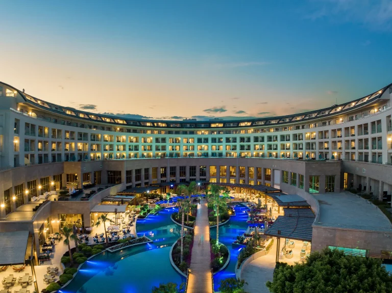 Kaya Palazzo Golf Resort at dusk with its pools lit